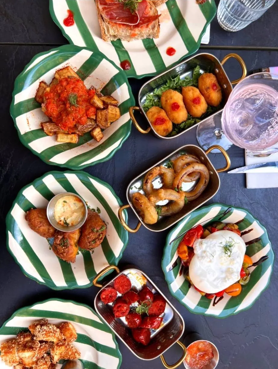 Une table de tapas : pan con tomate, patatas bravas, croquetas, oignons rings, burrata, chorizo grillé et poulet pané
